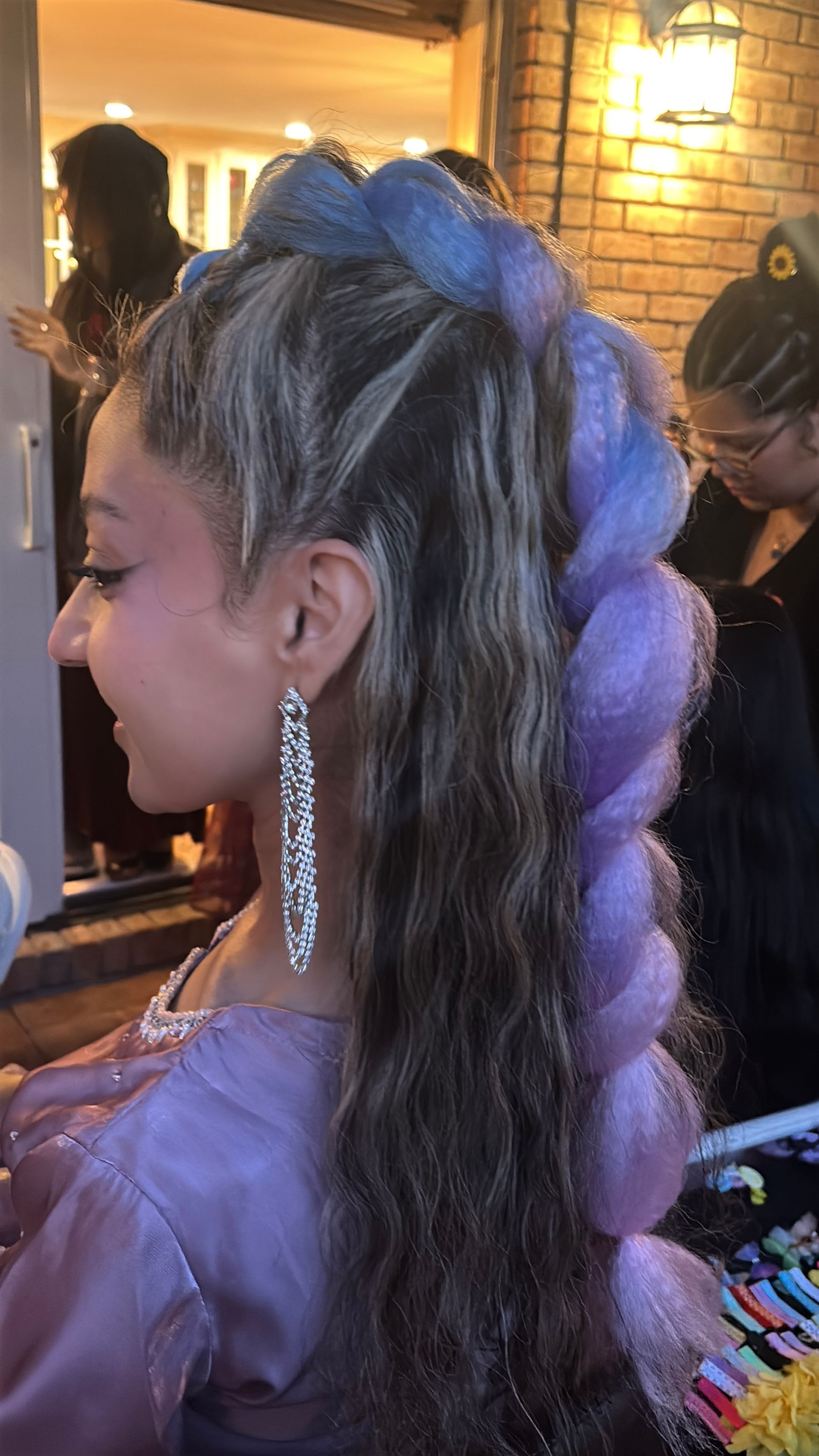 Woman with long, colorful braided hair and dangling earrings.