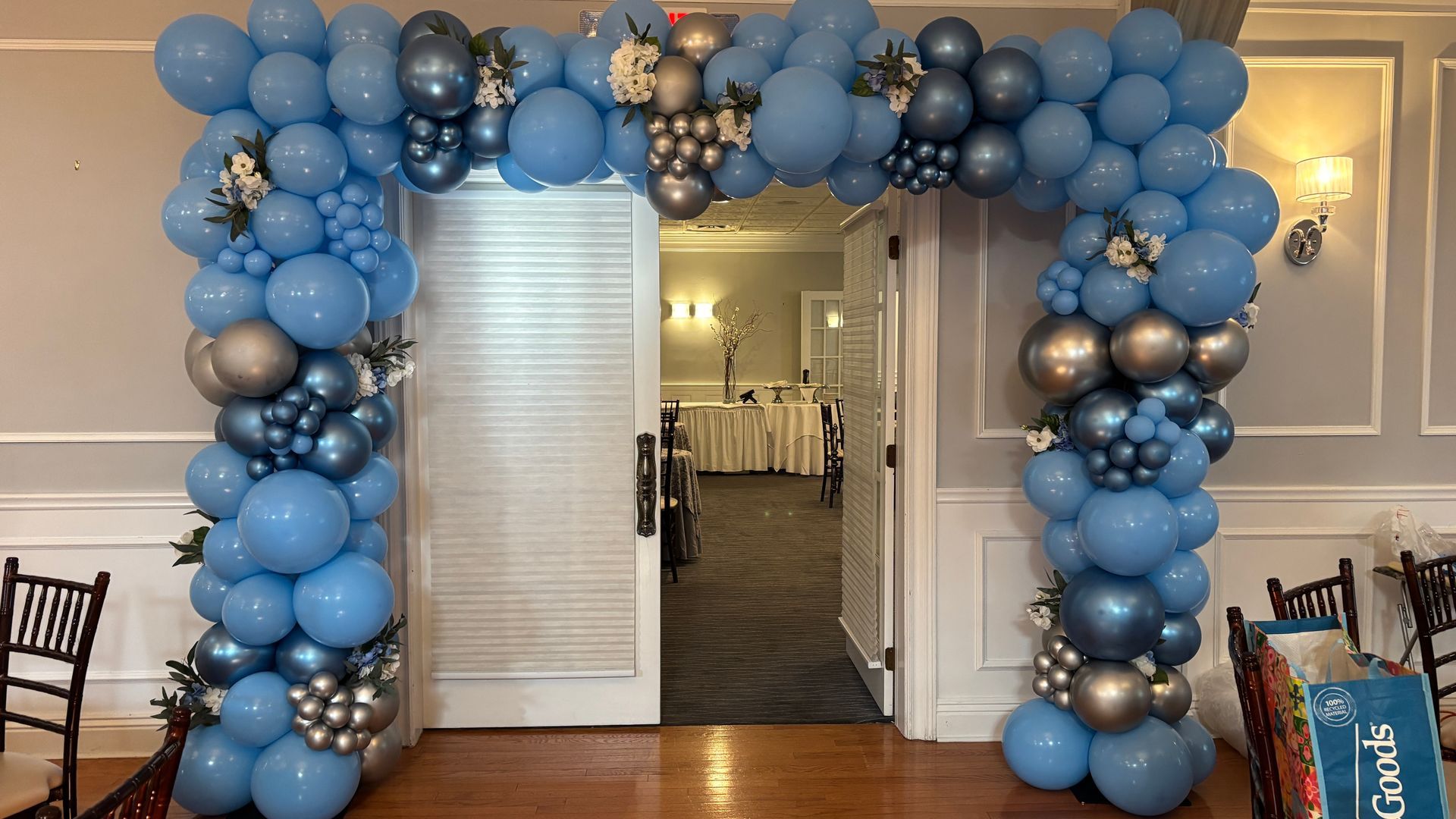 Blue and silver balloon archway over a doorway into a decorated room.