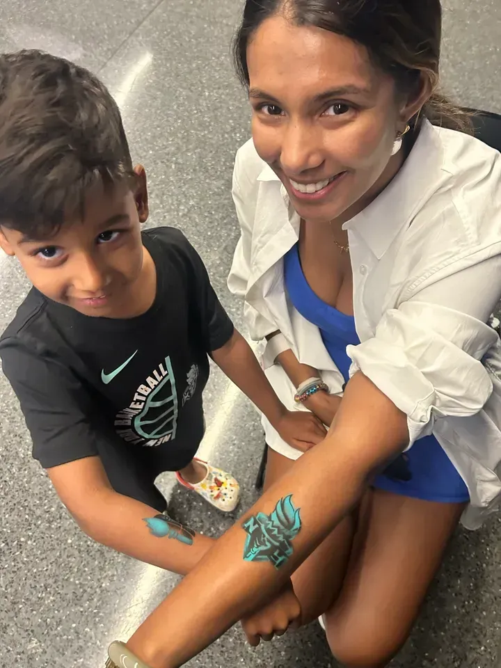 Woman and child show matching blue temporary tattoos on their arms.