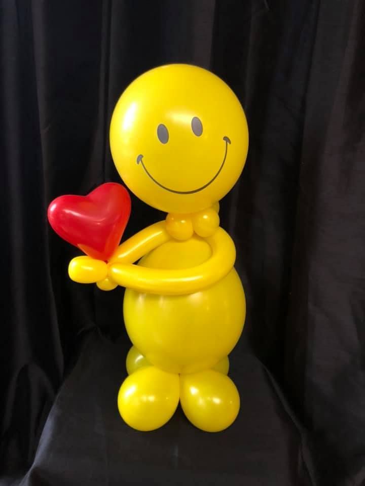 Yellow balloon figure with a smiley face, holding a red heart.