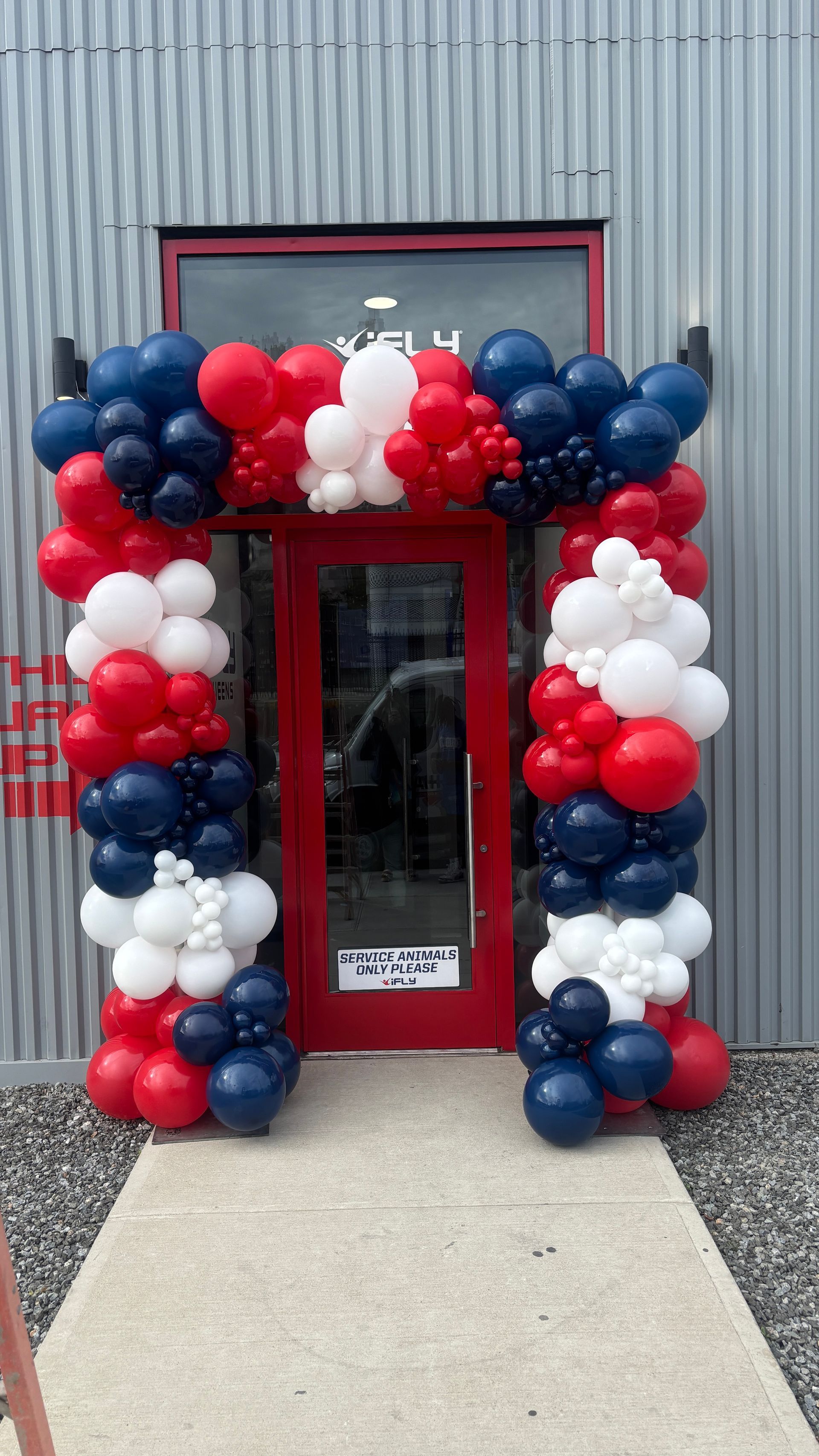 Red door with a balloon arch in red, white, and blue for iFLY Grand Opening in Long Island City.