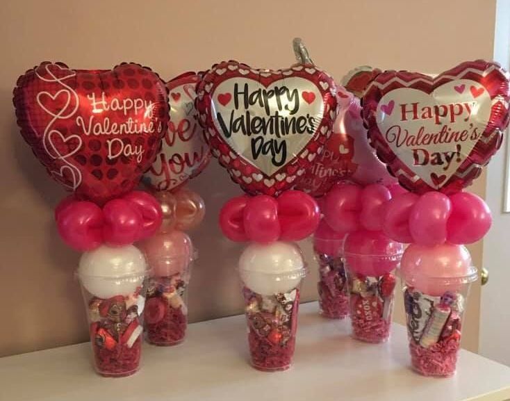 Valentine's Day balloon decorations: heart-shaped balloons, candy-filled cups, and pink and red balloons.