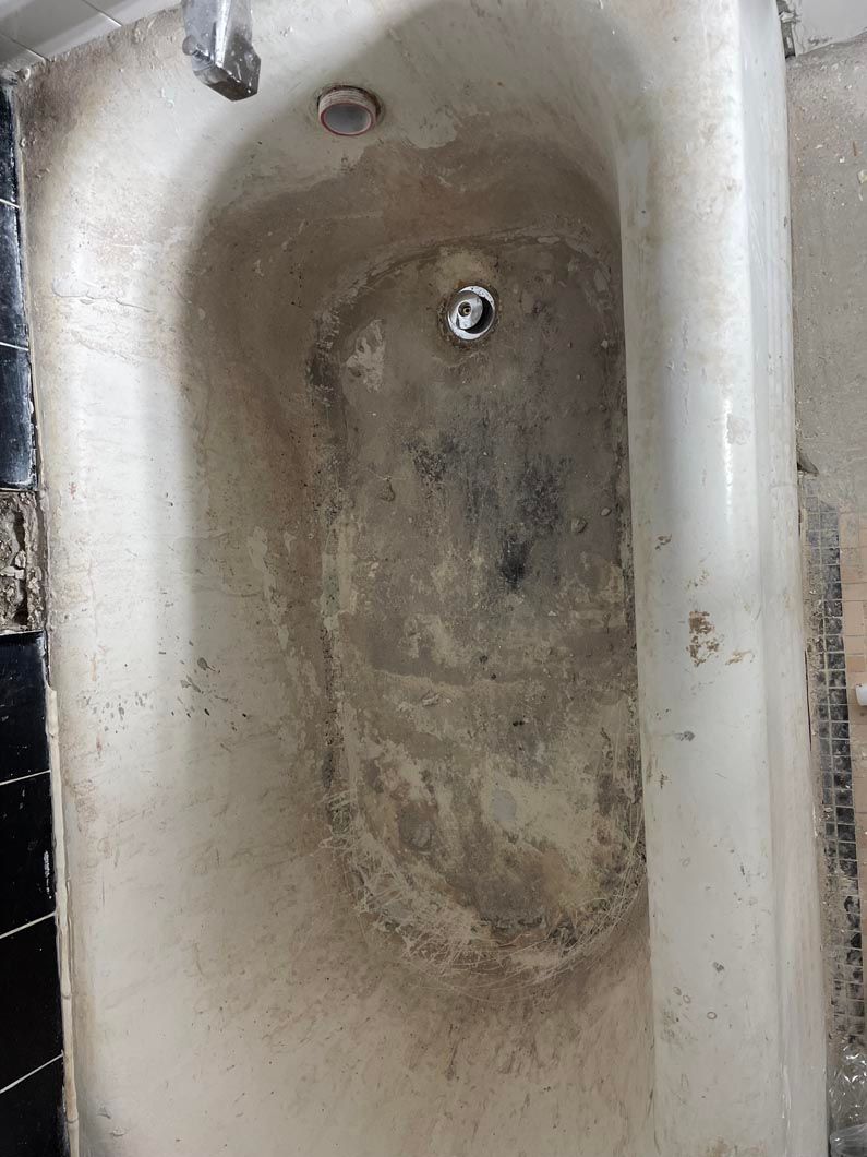 Dirty, stained bathtub with dark grime around the drain and rim