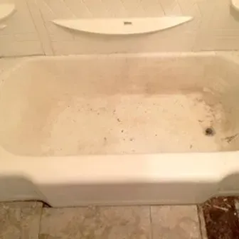 Dirty white bathtub with stains and debris in a tiled bathroom