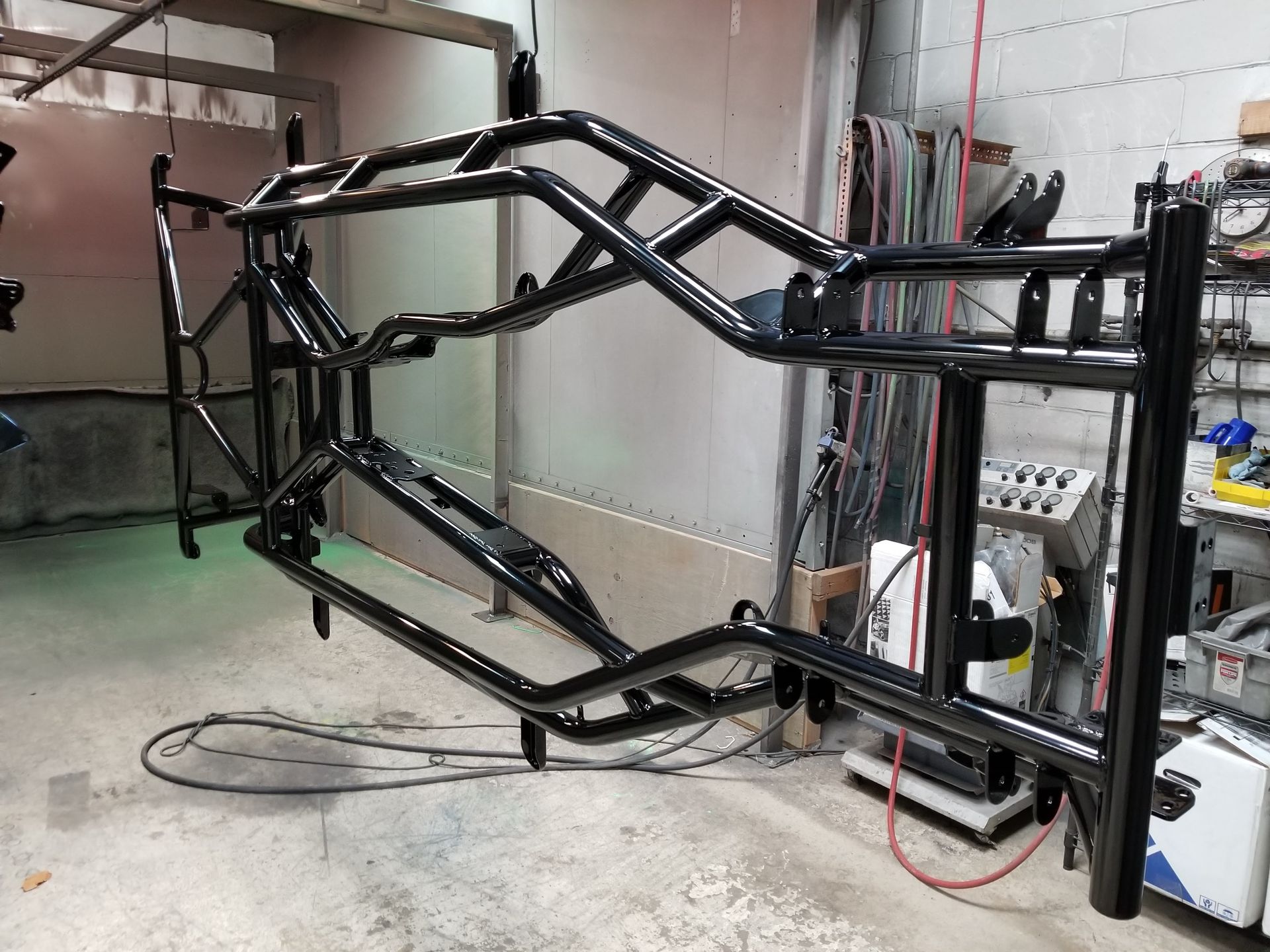 Black painted car rims hanging in a workshop; green hubs.