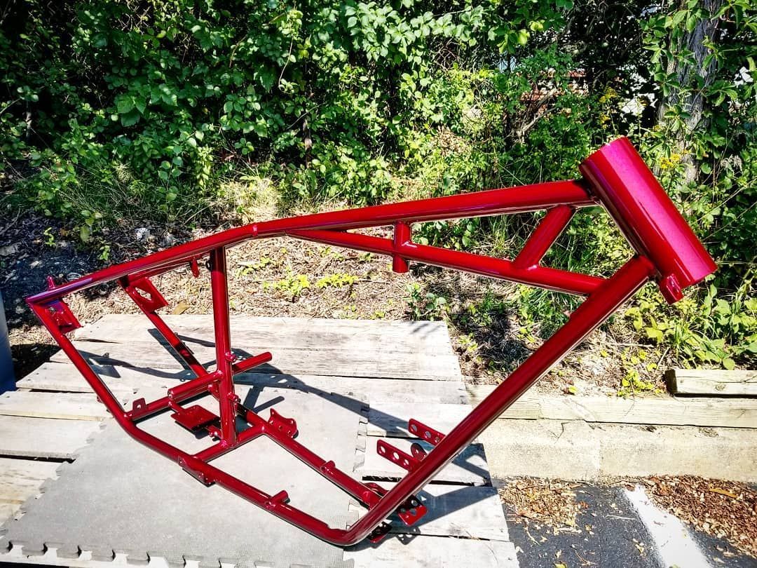 Red motorcycle frame outdoors against green foliage.