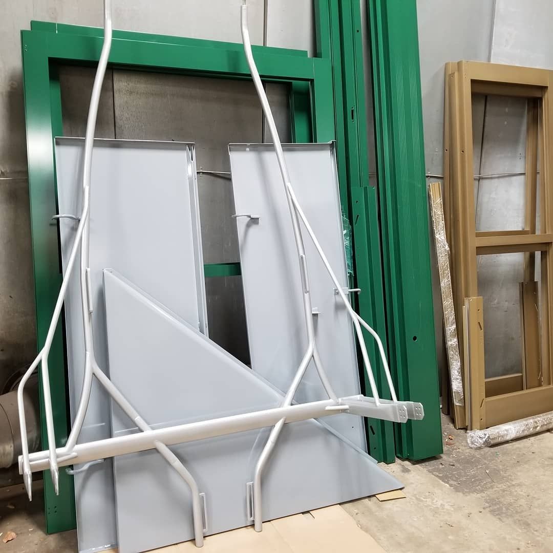 White metal swing set parts with green and brown window frames in a room.
