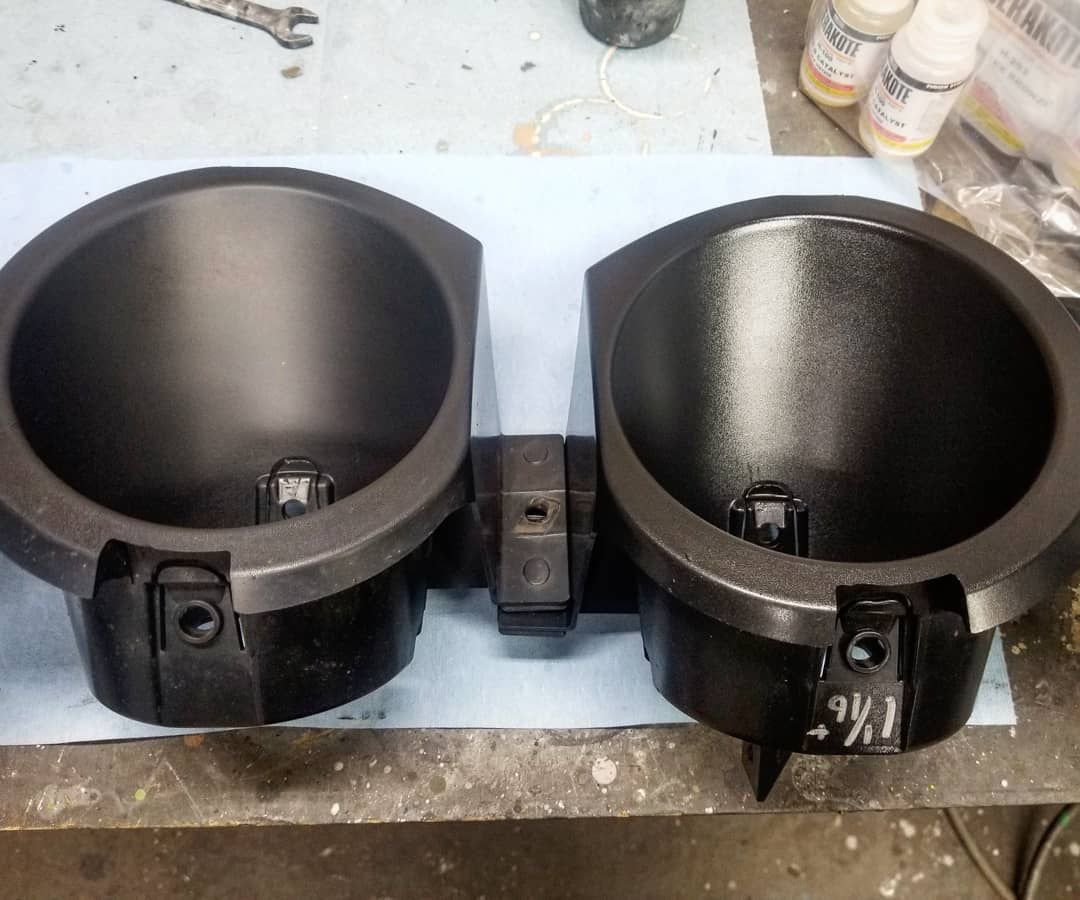 Two black plastic cup holders on a workbench.