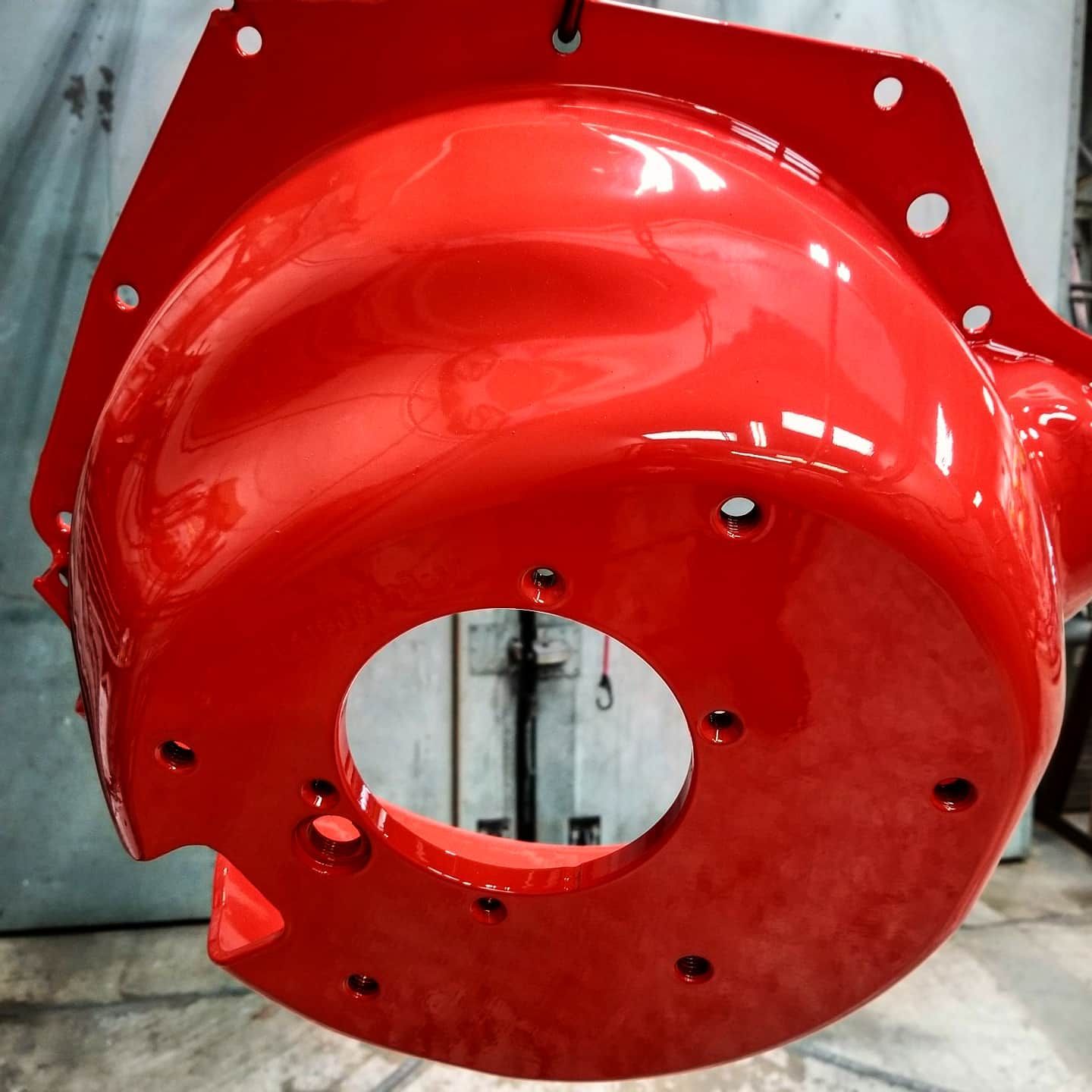 Bright red painted metal component with multiple holes.