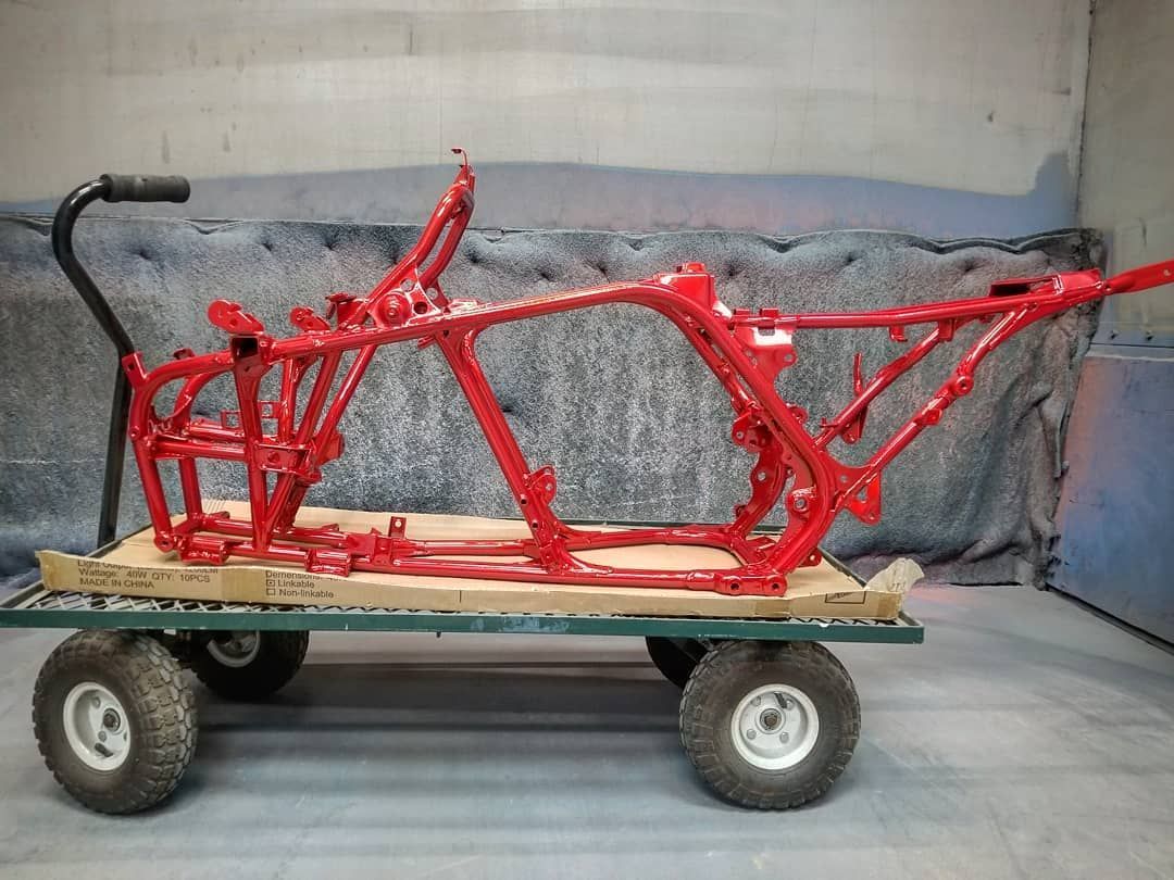 Red motorcycle frame on a cart, freshly painted.