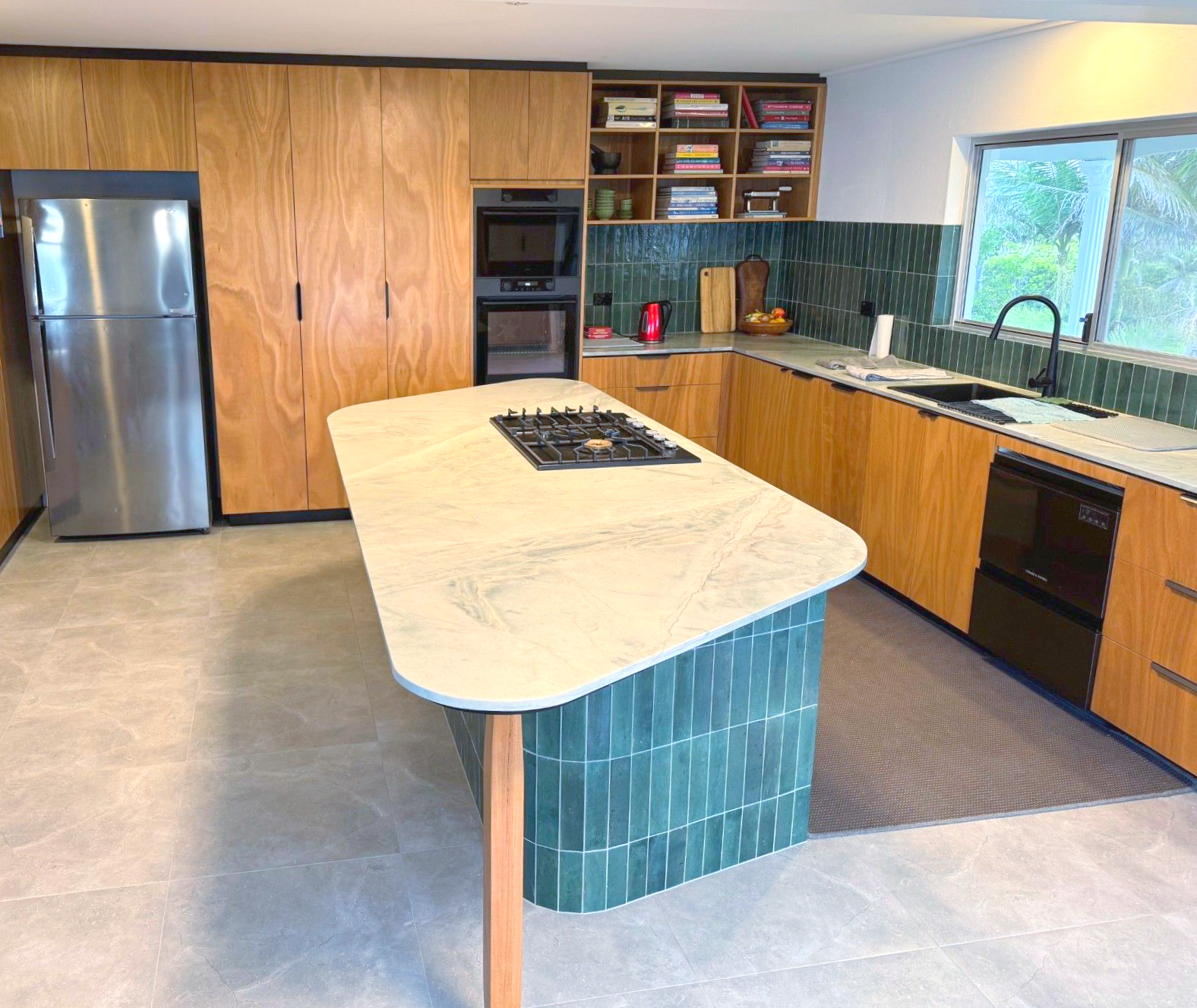 Modern kitchen with wooden cabinets, teal tile island, stainless steel appliances, and a window — Crispin Cabinetmakers in Grafton, NSW