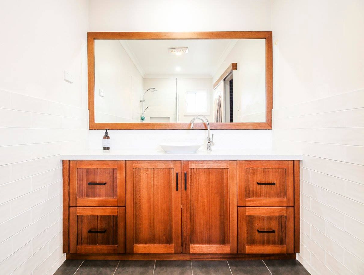 Bathroom with a white countertop, vessel sink, and wooden cabinets, with a large mirror framed in wood — Crispin Cabinetmakers in Grafton, NSW