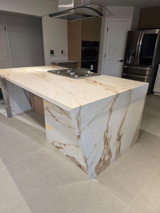 Kitchen island with marble-like countertop and cooktop.