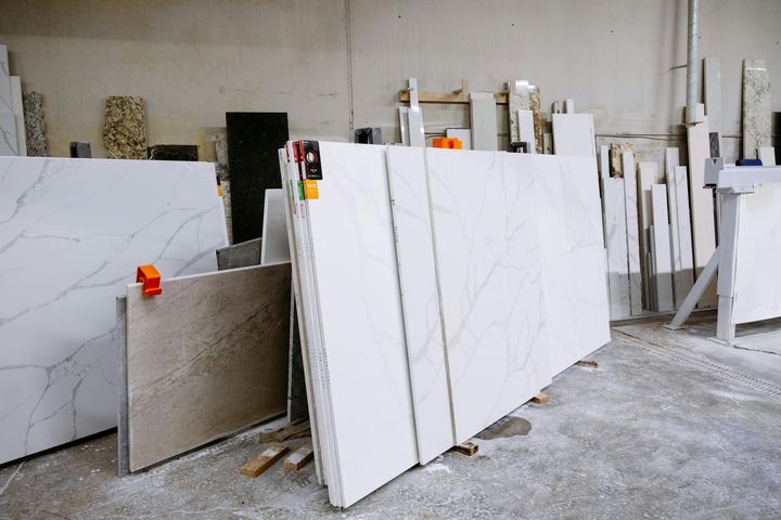 Slabs of white and beige stone leaned against a wall inside a warehouse.