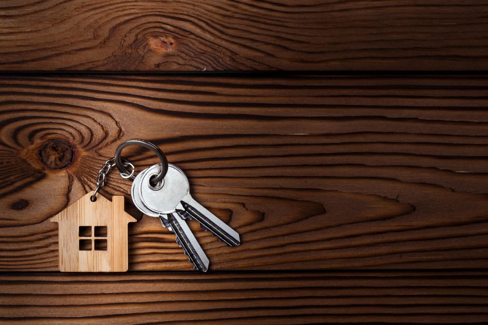 A Pair of Keys and a Wooden House Keychain on a Wooden Table — Darwin Lock & Key In Coconut Grove, NT