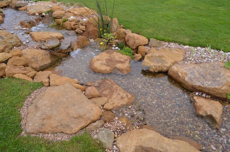 A stream surrounded by rocks and grass in a garden