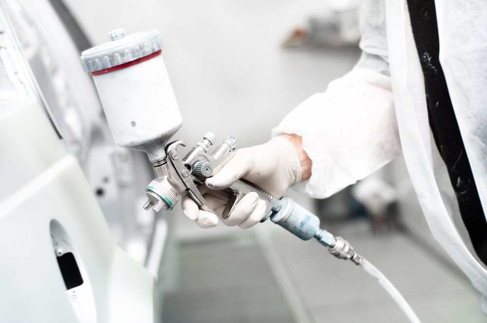 Close-Up of A Person Using a Spray Paint Gun on A White Car Body — Westside Panels & Towing in Prospect Vale, TAS