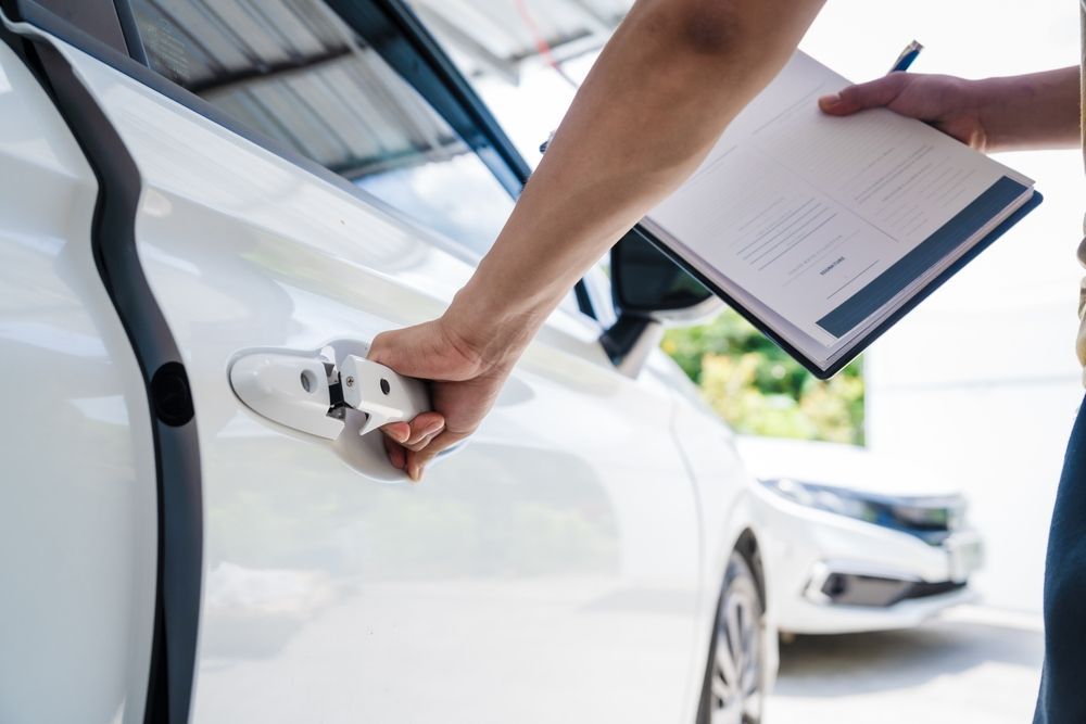 Hand holding a car key near a white car door, with a clipboard in the background — Westside Panels & Towing in Prospect Vale, TAS