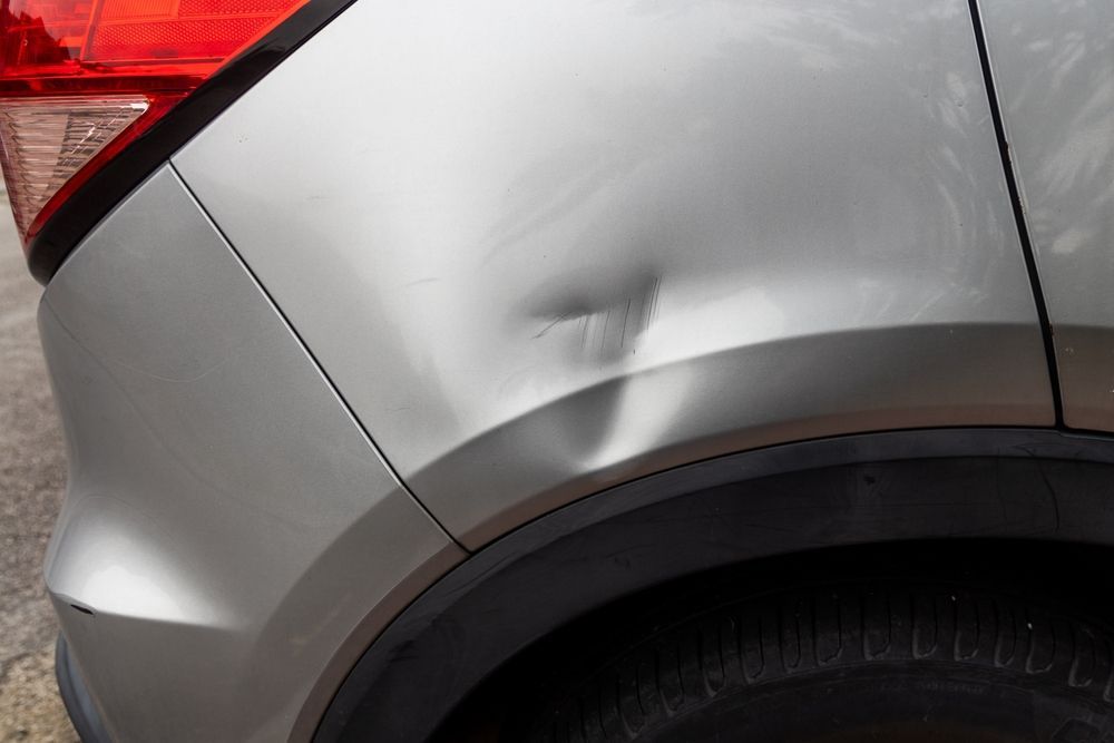 Dent and crease on the rear side panel of a silver car near the wheel — Westside Panels & Towing in Prospect Vale, TAS