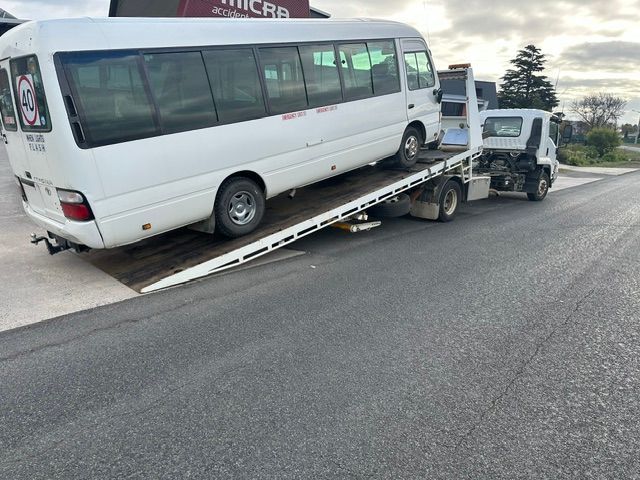 White minibus on a flatbed tow truck on a roadside— Westside Panels & Towing in Prospect Vale, TAS