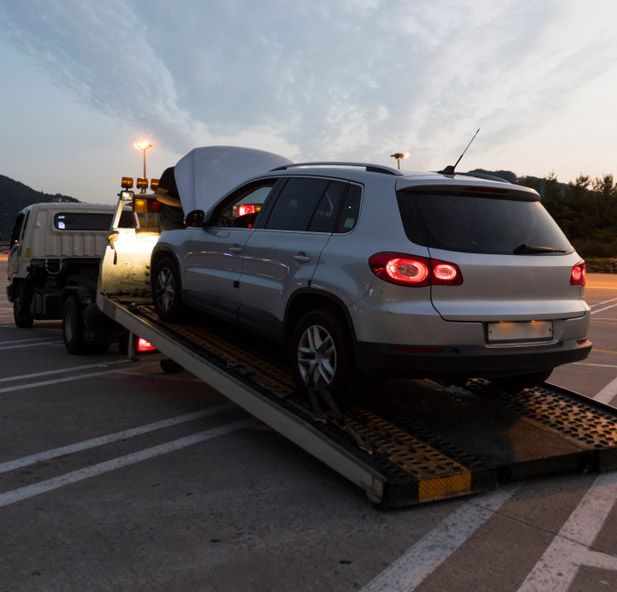 A Broken Down Vehicle Being Hoisted onto a Tilt Tray Truck — Westside Panels & Towing in Prospect Vale, TAS