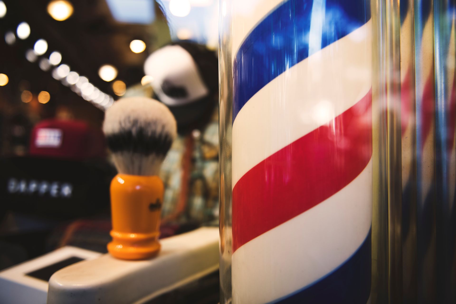 Barber shop scene with a striped pole, shaving brush, and blurry interior.