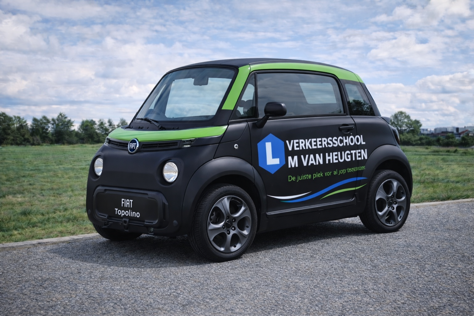 Een zwart-groene lesauto van de rijschool staat geparkeerd op een weg onder een bewolkte hemel.