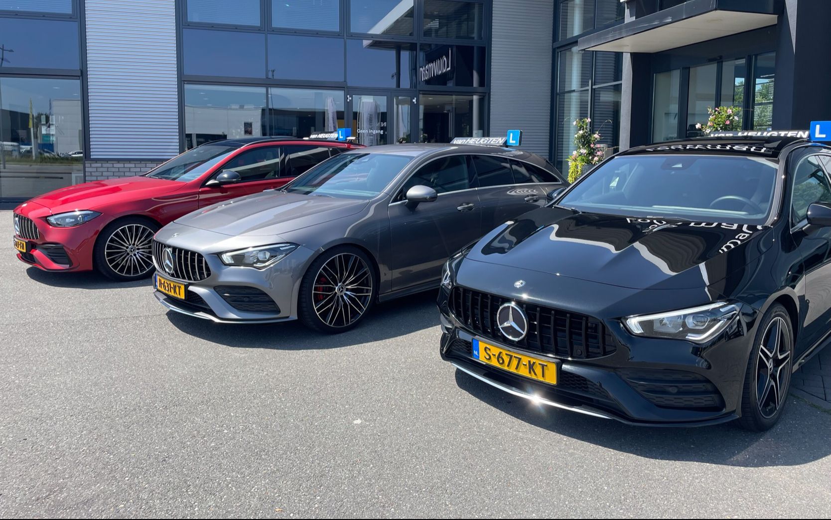 Drie geparkeerde sportauto's, waaronder een zwarte Mercedes, voor een autodealer.
