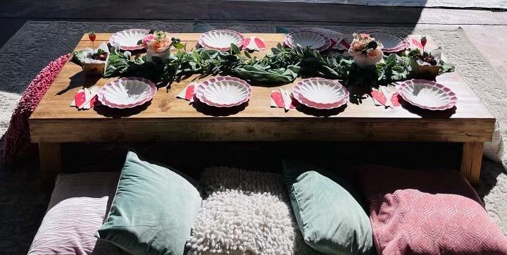 A wooden table with plates and pillows on it.