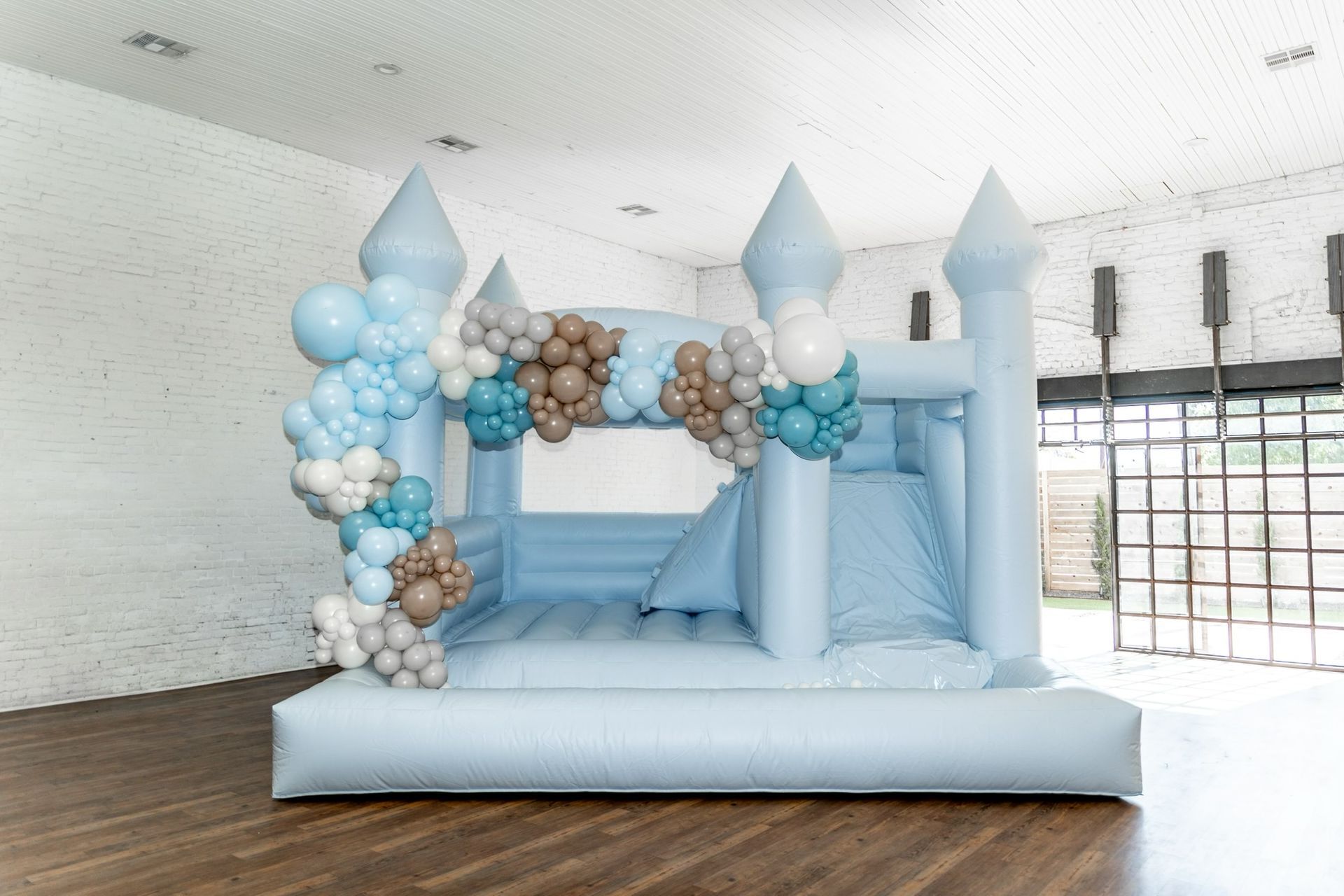 A blue bouncy castle decorated with balloons in a room.