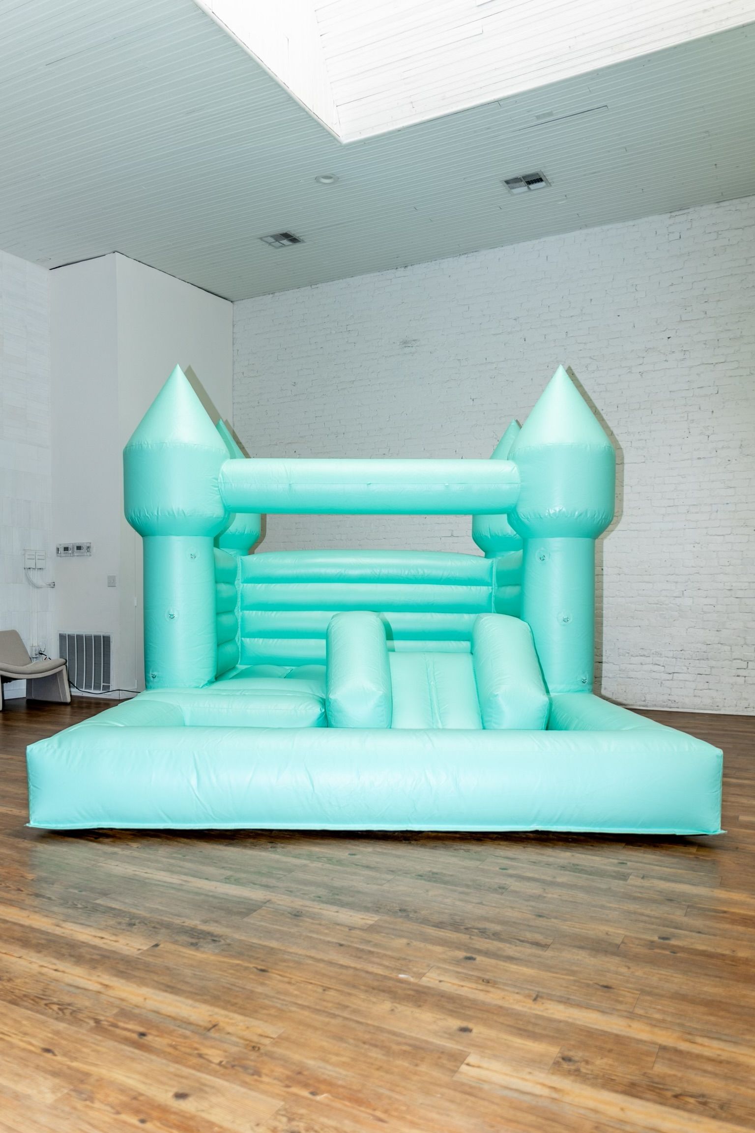 A blue bouncy castle is sitting on a wooden floor in a room.