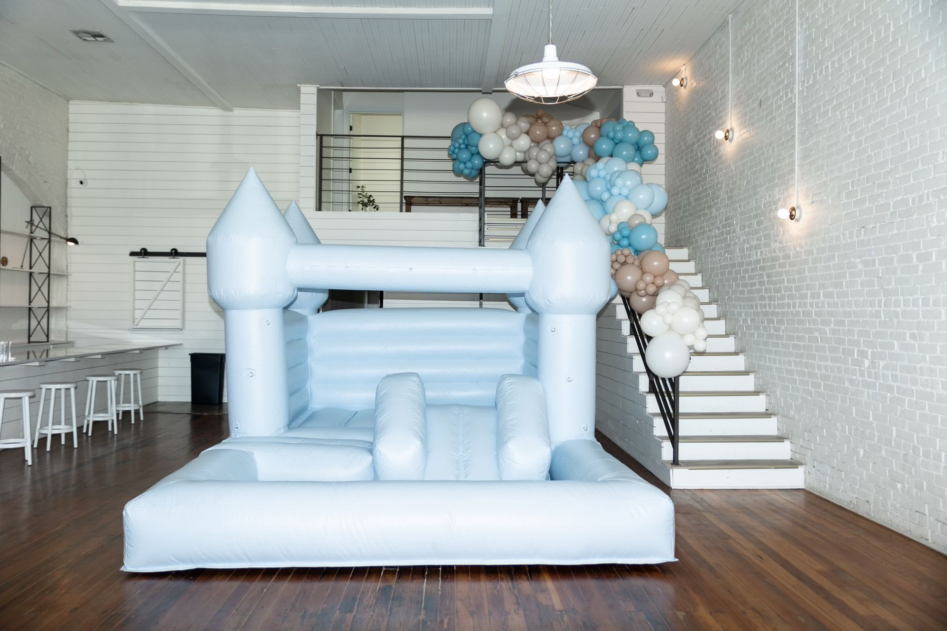A white bouncy castle is sitting in a room next to stairs.