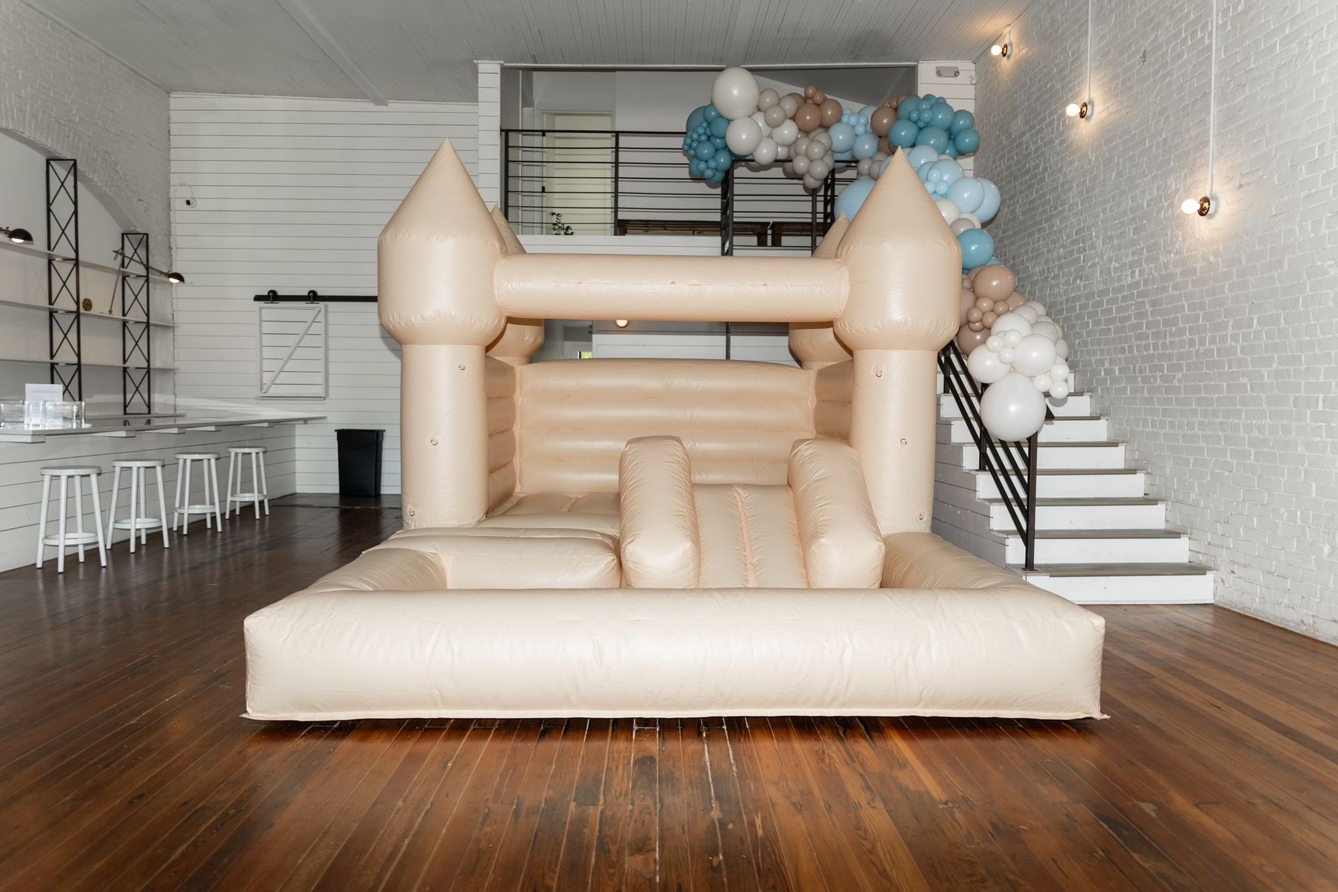 A white bouncy castle is sitting on a wooden floor in a room.