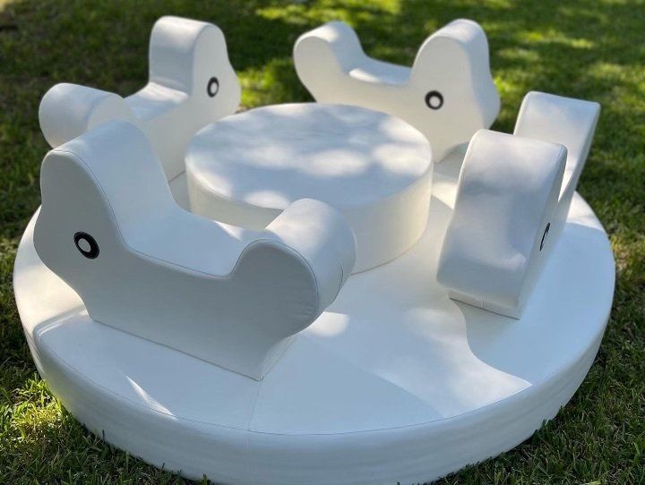 A white merry go round is sitting on top of a lush green field.