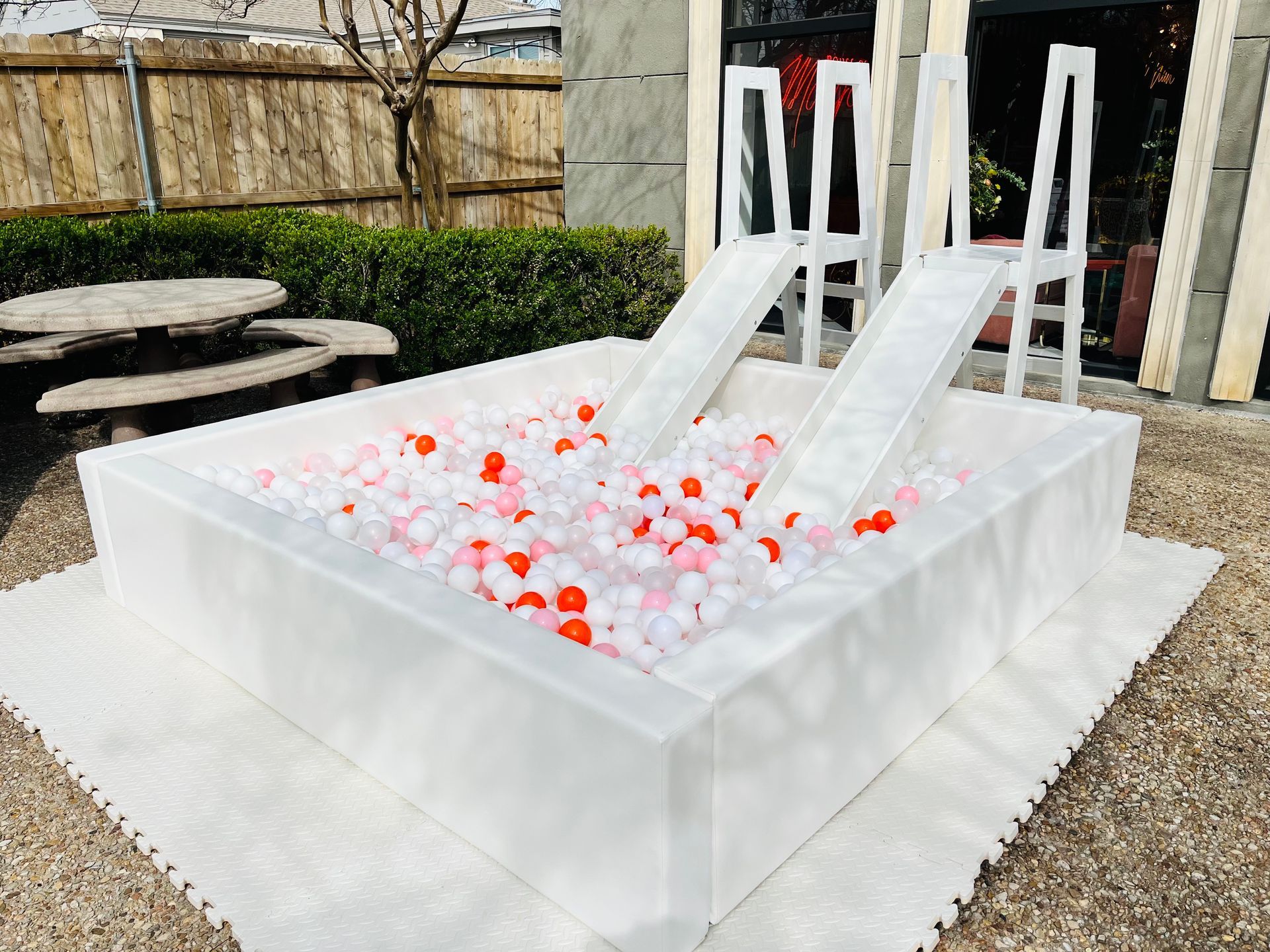 A white pool filled with red and white balls and a slide.
