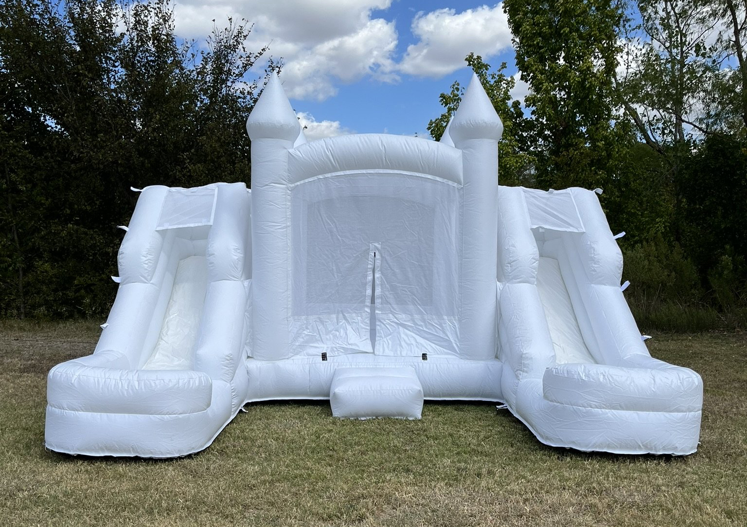 A white bouncy castle is sitting on top of a lush green field.