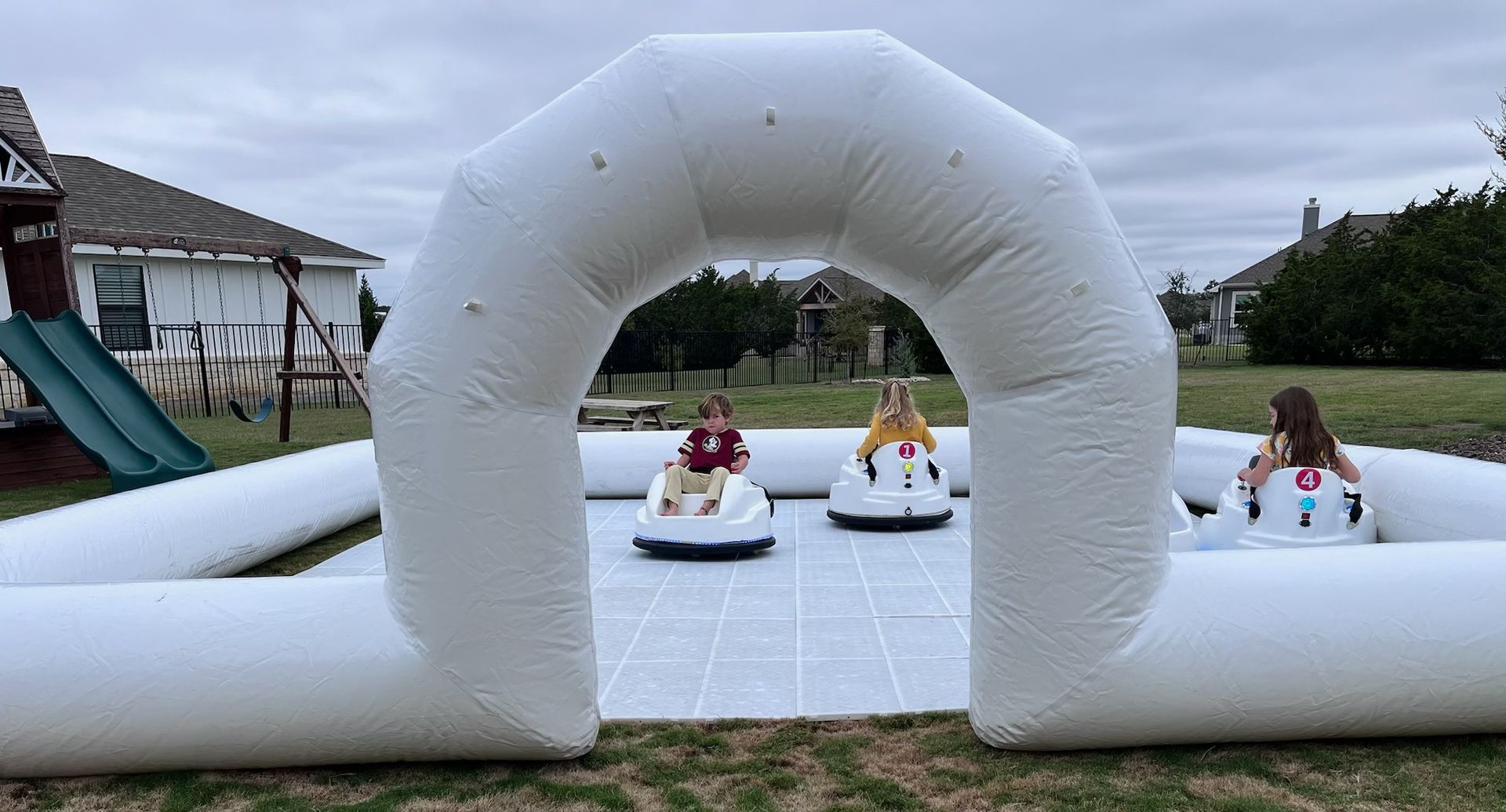 A group of children are riding a snowmobile through an inflatable archway.