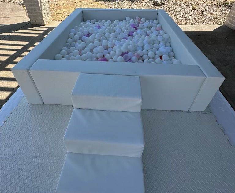A white ball pit with stairs leading up to it