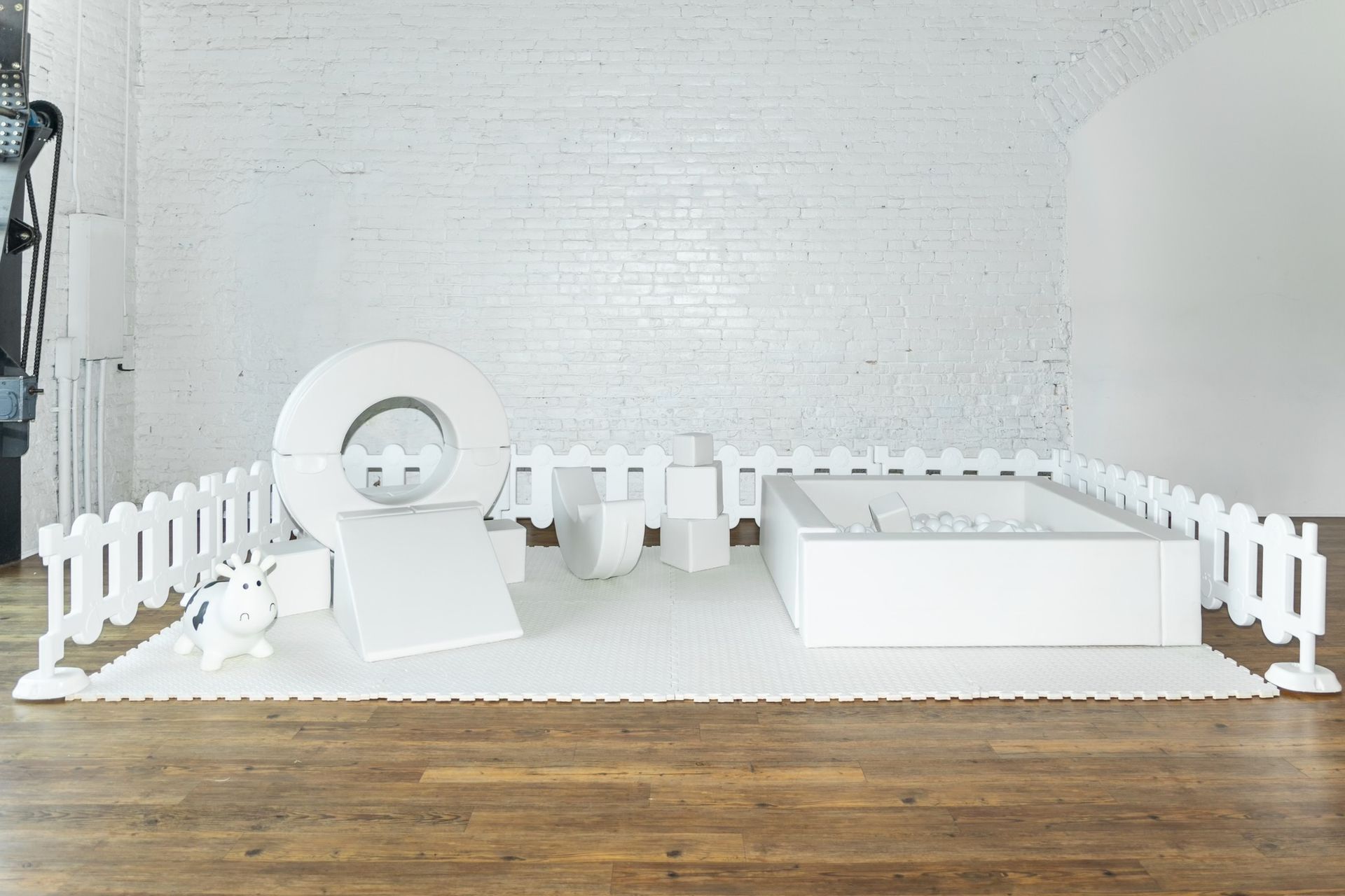 A room with a wooden floor and a white fence surrounding it.
