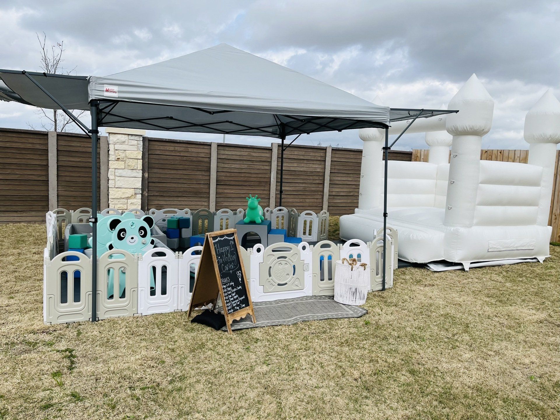 A white bouncy house is sitting under a tent in a field.