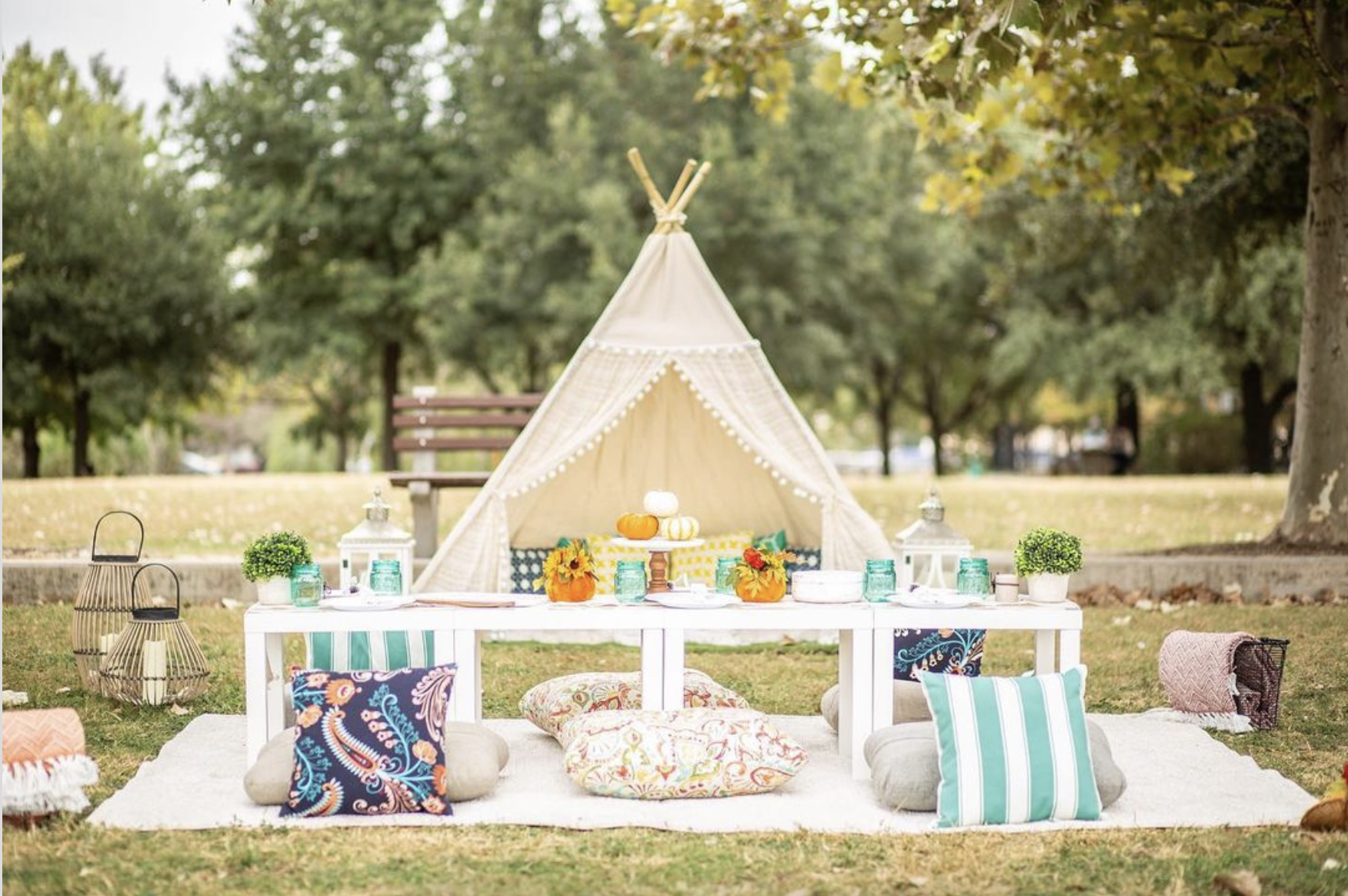 A teepee is sitting on top of a blanket in the middle of a field.