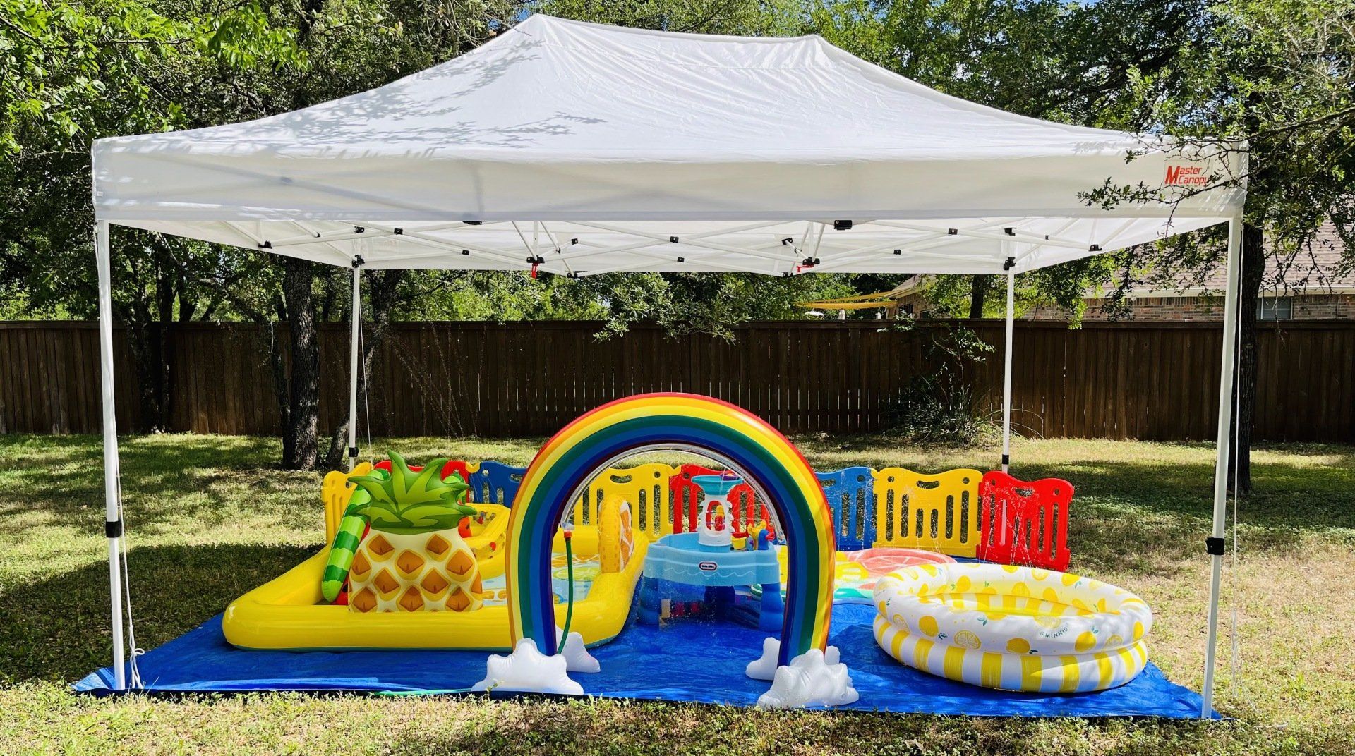 A white tent with a rainbow and a pool underneath it.