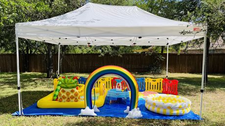 A white tent with a rainbow and a pool underneath it.