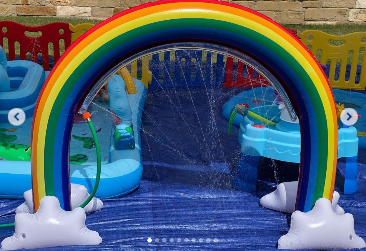 A rainbow shaped sprinkler is sitting on top of a blue tarp.