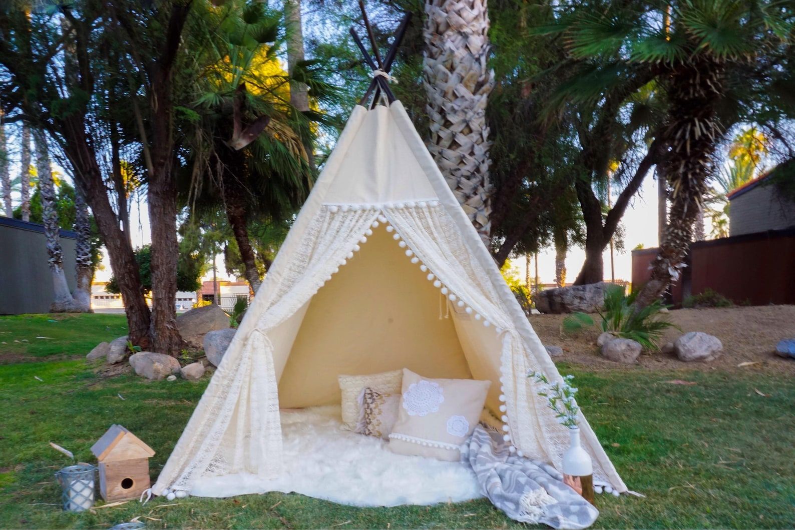 A white teepee is sitting on top of a lush green field.