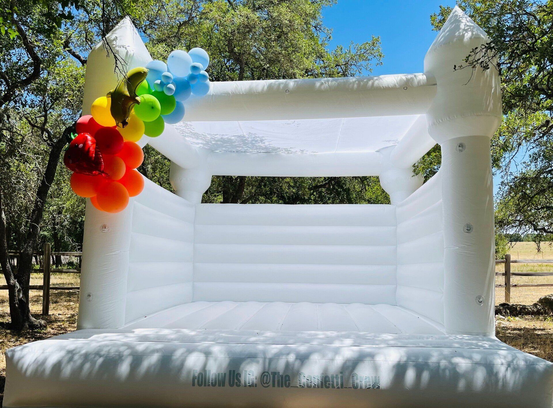 A white bouncy house with balloons on top of it.
