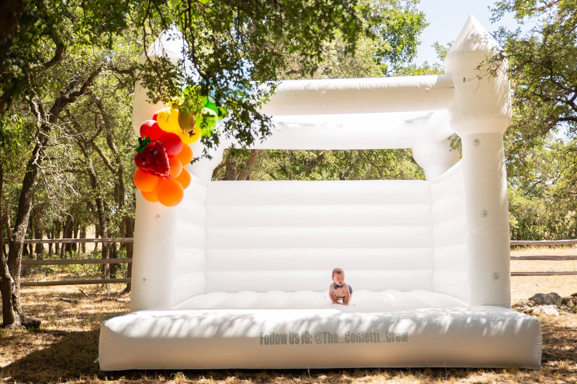 A baby is sitting on top of a white bouncy castle.