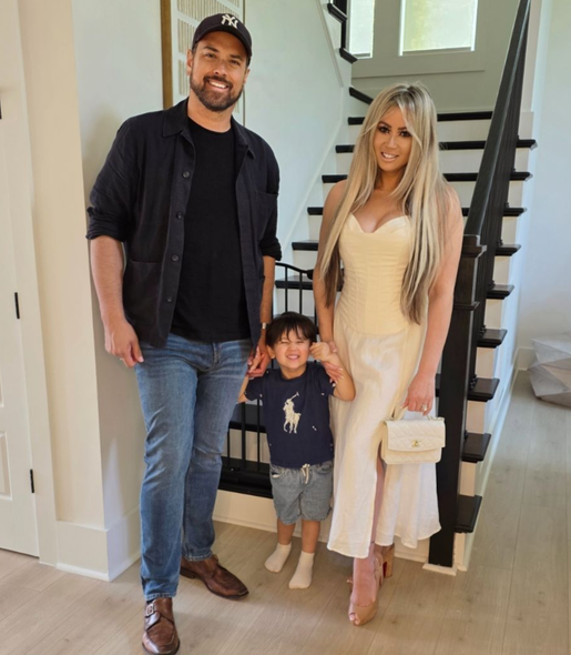 Del and his family stands inside by a staircase, smiling.
