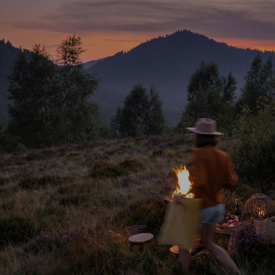 Persoon met brandende vuur en tas op weg naar een picknick in de schemering van de bergen.