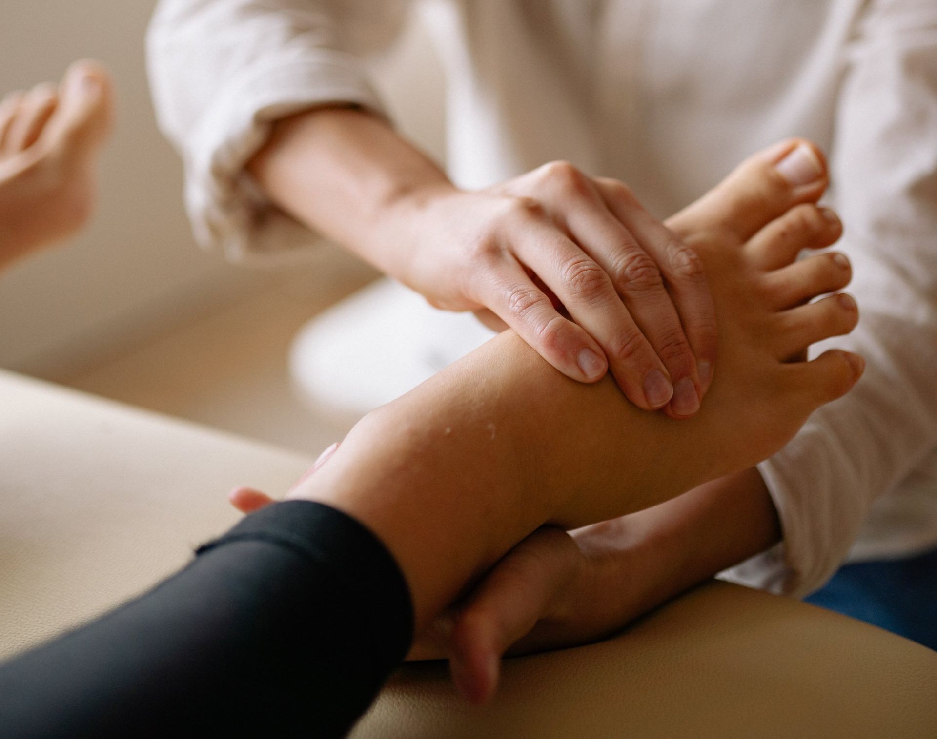 Handen geven een voetmassage op een behandeltafel.